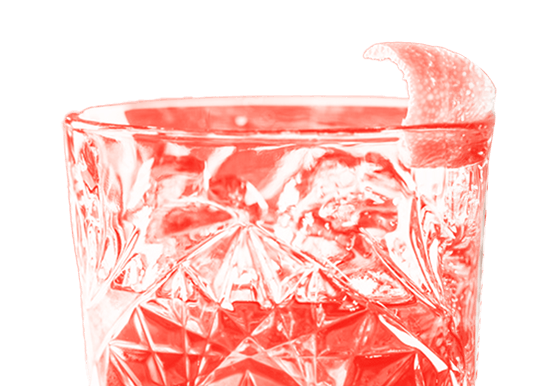 Ein rotes Lichtbad hebt ein kristallenes Trinkglas hervor, gefüllt mit einem Getränk und garniert mit einer Zitronenscheibe am Rand.